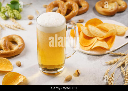 Ein Krug Bier und verschiedene Snacks rund-um-Brezeln, Chips und Pistazien. Stockfoto