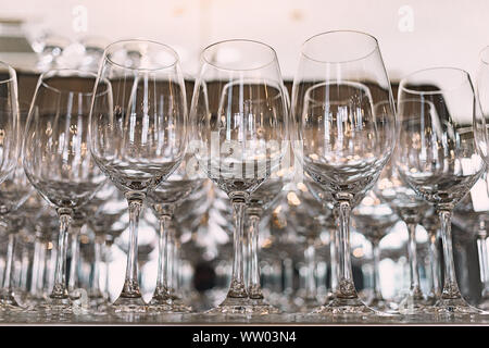 Viele Gläser auf einen Tisch. Leere Gläser in einer Reihe. Vielen leeren Likör Gläser. Viele leere Sektgläser hautnah. Glas Pokale auf dem weißen Stockfoto