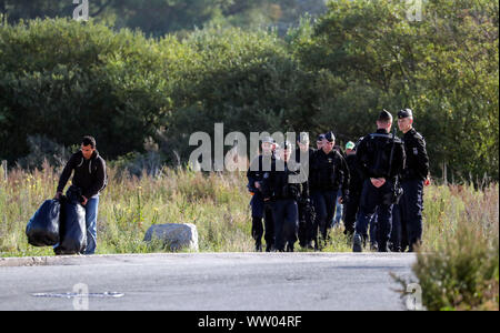 Französische Polizisten bewegen Migranten an einem Camp in Calais, Frankreich. Stockfoto