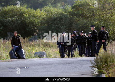 Französische Polizisten bewegen Migranten an einem Camp in Calais, Frankreich. Stockfoto