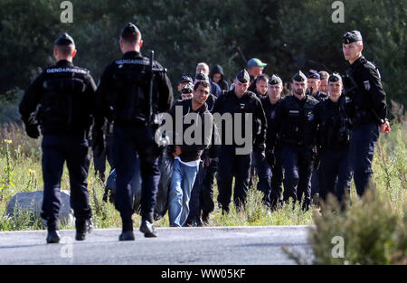 Französische Polizisten bewegen Migranten an einem Camp in Calais, Frankreich. Stockfoto