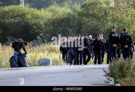 Französische Polizisten bewegen Migranten an einem Camp in Calais, Frankreich. Stockfoto