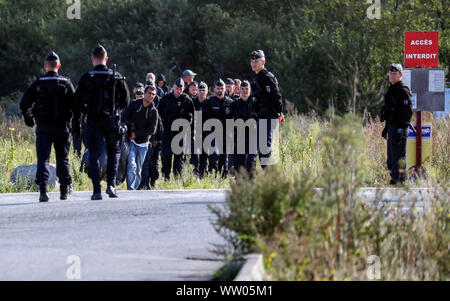 Französische Polizisten bewegen Migranten an einem Camp in Calais, Frankreich. Stockfoto