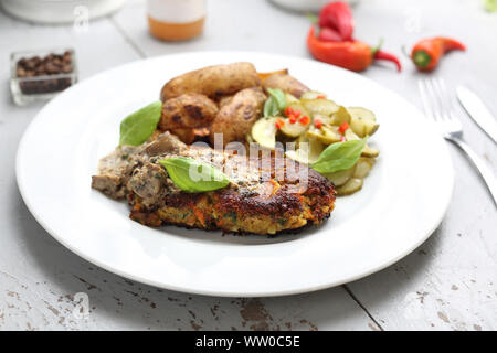 Linsen Schnitzel mit Pilzen mit Gurkensalat und Kartoffeln serviert Stockfoto