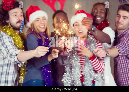 Multiethnische Gruppe junger happy and Business Leute Beleuchtung eine Wunderkerze und Spaß beim Silvester feiern in der betonwand an Stockfoto