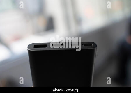 Man hält die Bank ein Ladegerät. Powerbank in der Hand. Strom sparenden Gerät für Smartphones und andere Geräte. Helfen Sie Ihr Telefon aufladen. Stockfoto