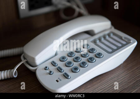 Weißen Jahrgang Telefon mit grauen battoms auf einem braunen Tisch im Hotel. Stockfoto