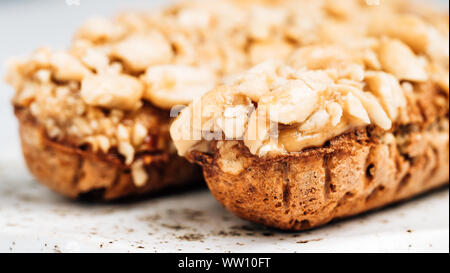 Hausgemachte eclairs mit peanut auf Marmor Hintergrund. Nahaufnahme der leckeren, gesunden profitroles mit Muttern. Kopieren Sie Platz für Text oder Design. Stockfoto