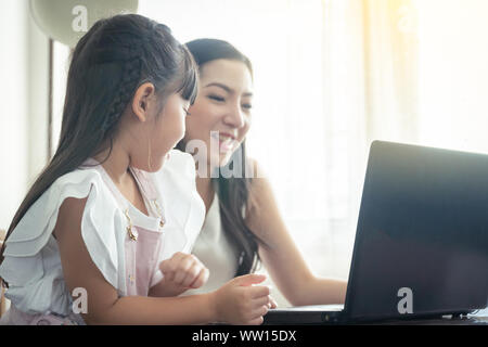 Schöne asiatische Mutter und Tochter gemeinsam arbeiten im Home Office am Fenster. im Konzept der einzelne Mamma oder Alleinerziehende.