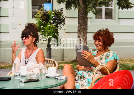 Treffen an einem Sommergarten Restaurant mit zwei Frauen über Kaffee und Zigaretten. Sie haben sich schon seit langer Zeit gesehen. Stockfoto