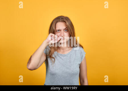 Brunette Mädchen im grauen T-Shirt über isolierte orange Hintergrund zeigt Emotionen Stockfoto