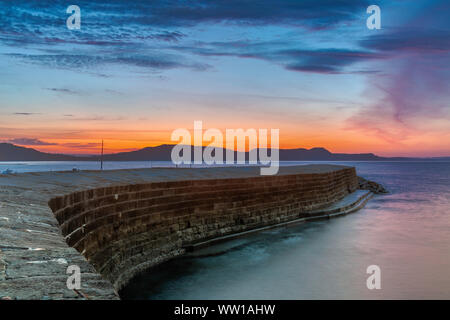 Lyme Regis, Dorset England Sonnenaufgang am Cobb, das 14. Jahrhundert Hafenmauer von Lyme Regis Stockfoto