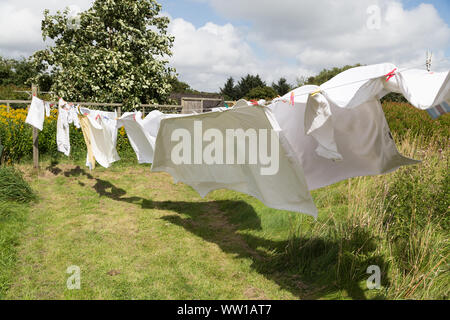 Wäscheleine mit weißer Bettwäsche an einem windigen Tag Stockfoto