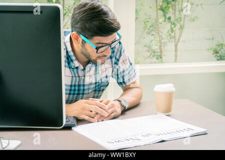 Junge casual Geschäftsmann lesen Business News in den Morgen im Home Office. Stockfoto