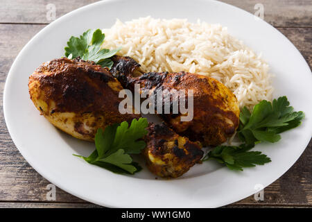 Gebratene Tandoori Chicken mit Basmati Reis in der Platte auf hölzernen Tisch. Stockfoto