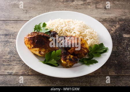 Gebratene Tandoori Chicken mit Basmati Reis in der Platte auf hölzernen Tisch. Stockfoto