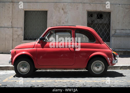Rom, Italien, 7. Juli 2018: Eine rote 2-Türer antiken Fiat Auto sitzt in der Sonne auf einem Stein Straße in Rom. Stockfoto