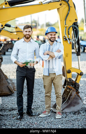Builder Wahl schwere Maschinen für Bau, im Gespräch mit einem Verkaufsberater im Freigelände der einen Shop mit speziellen Fahrzeugen Stockfoto