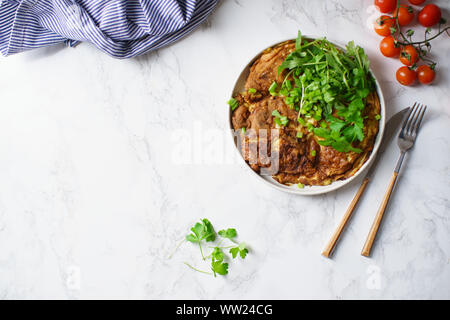 Tortilla Omelette mit in Scheiben geschnittenen Kartoffeln und Kräutern auf Marmor tisch Stockfoto