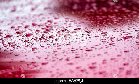 Eine Nahaufnahme von Wassertropfen auf einem roten Karosserie. Stockfoto