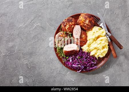 Crepinette, gebratene Flachbild Würstchen oder Pasteten von Hackfleisch und in einem Netz Fett gewickelt, serviert auf einem Teller mit Kartoffelbrei und Rotkohl Salat, Französisch Stockfoto