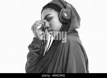 Portrait von wunderschönen afrikanischen brunette teenage Mädchen mit Dreadlocks tragen einen roten windbreaker Musik hören über kabellose Kopfhörer auf dem Bolzen isoliert Stockfoto