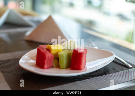 Obstsalat, in Scheiben geschnittenen Wassermelone, Melone und Ananas auf den Plätzen. Geschnittenes Obst auf einem Teller. Stockfoto