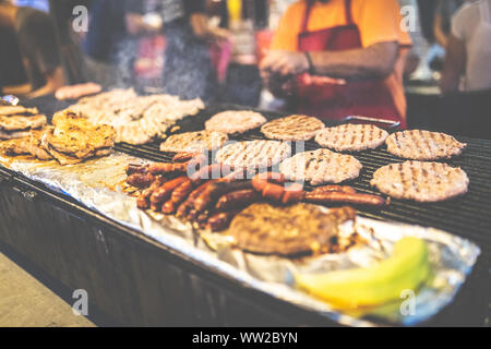 Der Küchenchef bereitet Burger und Würstchen an Street Festival. Stockfoto