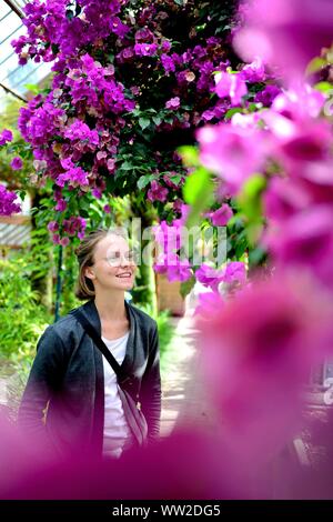 Eine junge Frau hinter blühenden Blumen in einem Glashaus am historischen Botanischen Garten im Stadtzentrum von Utrecht (Niederlande), 01. September 2019. | Verwendung weltweit Stockfoto