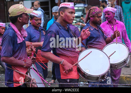 Eine Gruppe von Trommlern in farbigen Gulal (gulaal) Pulver bedeckt, in einer Prozession während Ganesh Chaturthi (Ganesh Festival) in Mumbai, Indien Stockfoto