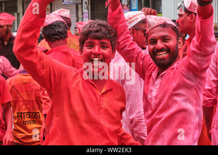 Fröhliche Teilnehmer in Rot (gulaal Gulal) Pulver bedeckt, in einer Prozession während Ganesh Chaturthi (Ganesh Festival) in Mumbai, Indien Stockfoto