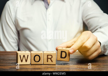 Mann legt einen hölzernen Blöcke mit der Aufschrift Wort. Die strukturelle Einheit der Sprache. Die Morphologie. Wortbildung. Studium der Grammatik. Sprachwissenschaft Stockfoto