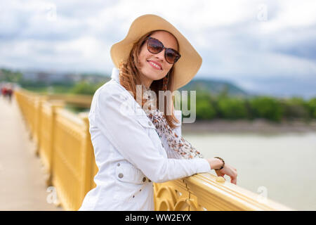 Natürliche Schönheit Frau in Hut lächelnd und entspannt auf Brücke über die Donau, Margaret Brücke, Budapest, Ungarn Stockfoto