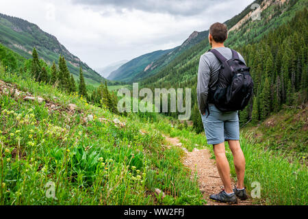 Mann, am Valley View auf Rätsel Creek Trail in Aspen, Colorado im Jahr 2019 Sommer mit grünen üppigen Pflanzen an bewölkten Tag und Schmutz der Straße Stockfoto