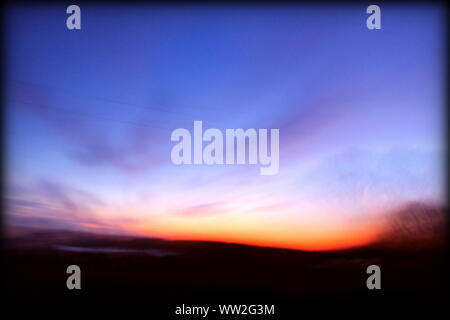 Verträumt und magische Szene bei Sonnenaufgang aus einem fahrenden Auto genommen, verschwommenen Landschaft Stockfoto