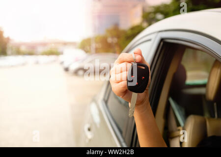 Die Hand einer Frau mit einem Auto Schlüssel zu der Fahrer dieses Auto eingereicht werden. Stockfoto