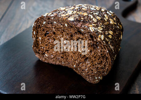 Malz Brotscheiben mit Hafer und Leinsamen auf dunklen Holz- Board. Bio Bäckerei Essen. Stockfoto