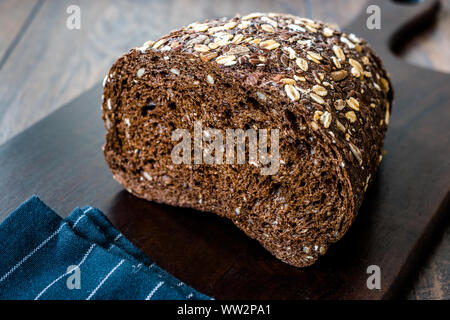 Malz Brotscheiben mit Hafer und Leinsamen auf dunklen Holz- Board. Bio Bäckerei Essen. Stockfoto