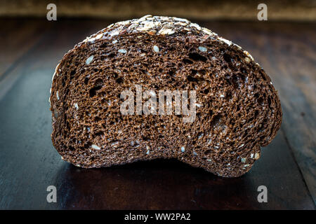 Malz Brotscheiben mit Hafer und Leinsamen auf dunklen Holz- Board. Bio Bäckerei Essen. Stockfoto