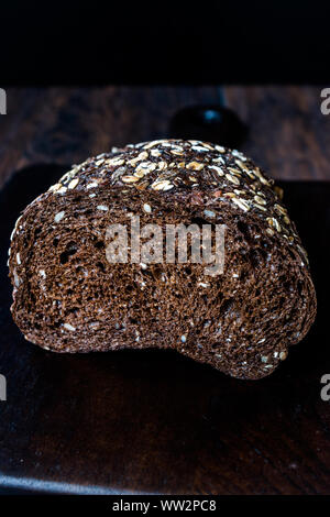 Malz Brotscheiben mit Hafer und Leinsamen auf dunklen Holz- Board. Bio Bäckerei Essen. Stockfoto