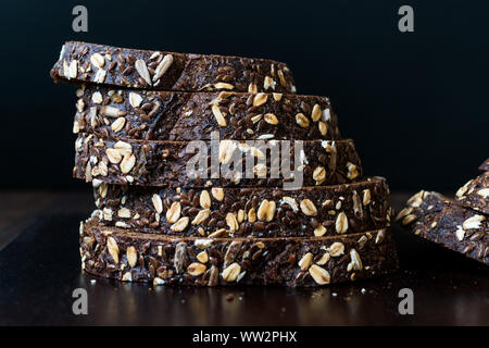 Malz Brotscheiben mit Hafer und Leinsamen auf dunklen Holz- Board. Bio Bäckerei Essen. Stockfoto