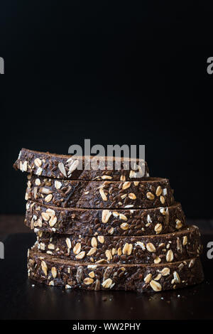 Malz Brotscheiben mit Hafer und Leinsamen auf dunklen Holz- Board. Bio Bäckerei Essen. Stockfoto