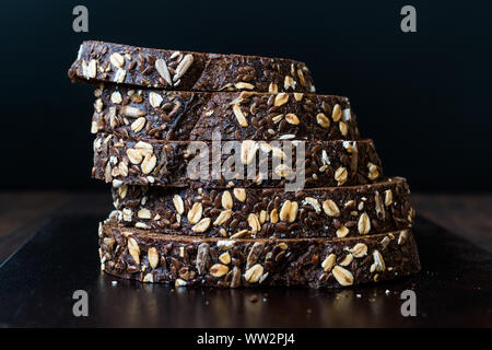 Malz Brotscheiben mit Hafer und Leinsamen auf dunklen Holz- Board. Bio Bäckerei Essen. Stockfoto