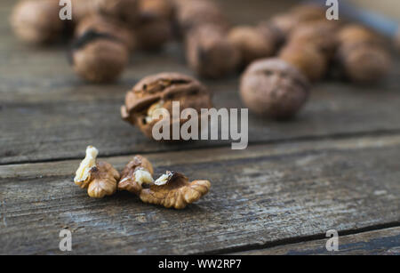 Ganze und gehackte Walnüsse auf hölzernen Tisch. Stockfoto