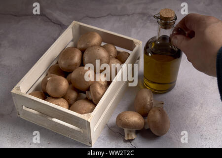 Gruppe von Portobello Pilze in einer Holzkiste neben einem Öl jar Stockfoto