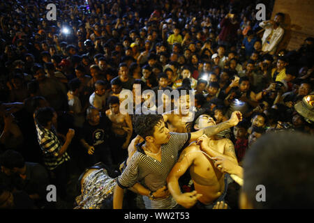 Kathmandu, Nepal. 12 Sep, 2019. Nepalesische jugendliche Kampf Alkohol aus dem Mund der Gottheit Bhairav Swet während Indra Jatra Festival zu trinken bei Hanumandhoka in Kathmandu, Nepal am Donnerstag, 12. September 2019. Credit: Skanda Gautam/ZUMA Draht/Alamy leben Nachrichten Stockfoto