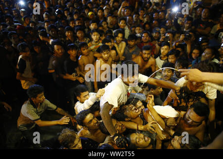 Kathmandu, Nepal. 12 Sep, 2019. Nepalesische jugendliche Kampf Alkohol aus dem Mund der Gottheit Bhairav Swet während Indra Jatra Festival zu trinken bei Hanumandhoka in Kathmandu, Nepal am Donnerstag, 12. September 2019. Credit: Skanda Gautam/ZUMA Draht/Alamy leben Nachrichten Stockfoto