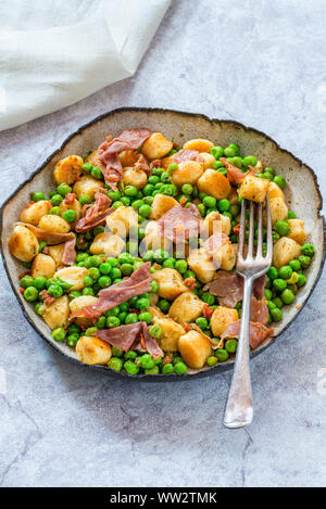 Gnocchi mit grünen Erbsen, Pesto, Schinken und Chorizo in eine Schüssel geben. Stockfoto