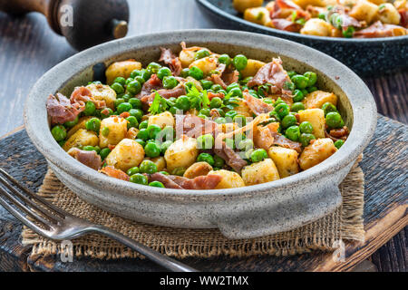 Gnocchi mit grünen Erbsen, Pesto, Schinken und Chorizo in eine Schüssel geben. Stockfoto