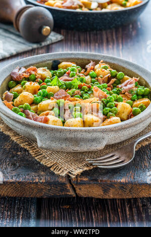 Gnocchi mit grünen Erbsen, Pesto, Schinken und Chorizo in eine Schüssel geben. Stockfoto